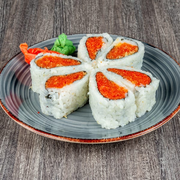 Six pieces of sushi with red filling arranged in a flower shape on a gray plate with ginger and wasabi.